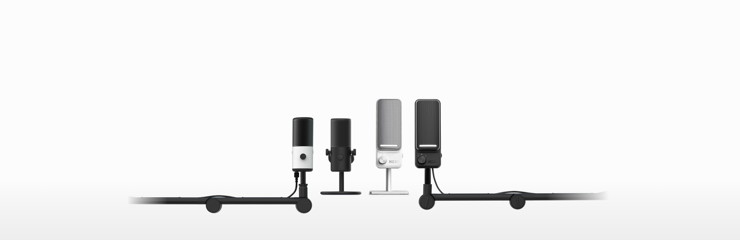 Five microphones of varying sizes and colors (black, white, and gray) are displayed on stands in a row against a plain white background.