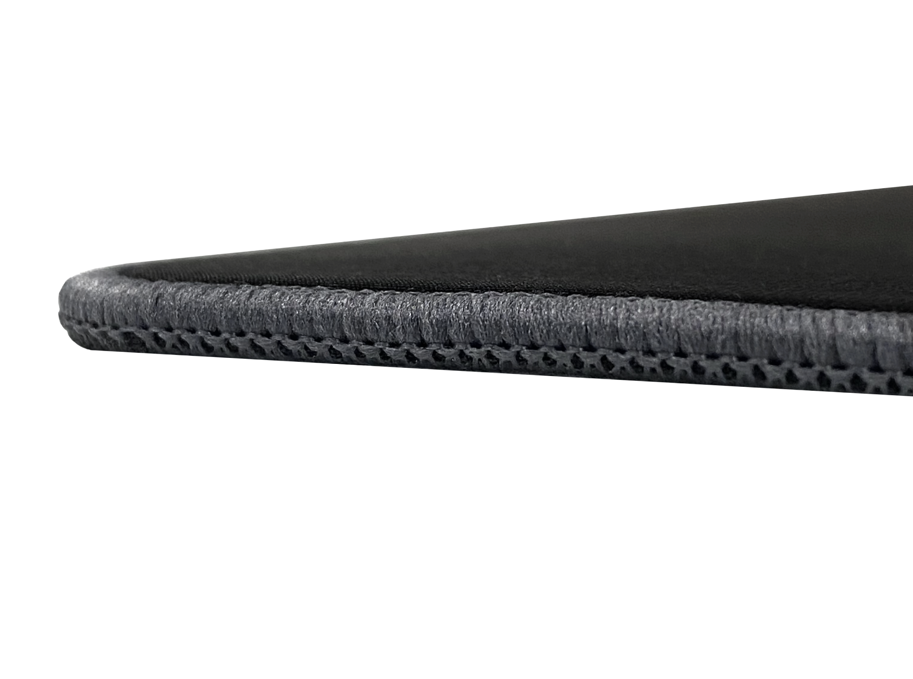 Close-up view of the edge of a black mouse pad, showing its stitched border and textured surface against a black background.