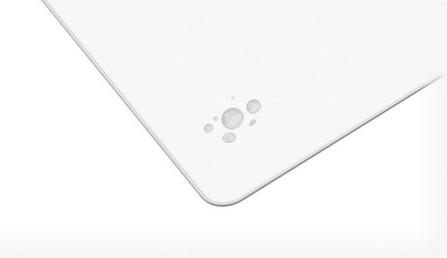 A close-up of the corner of a white rectangular object, possibly a tablet or board, featuring an embossed design of three small circles resembling bubbles.